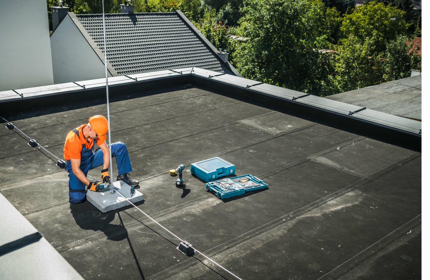 Engineer installing a lightning protection air terminal on a flat roof