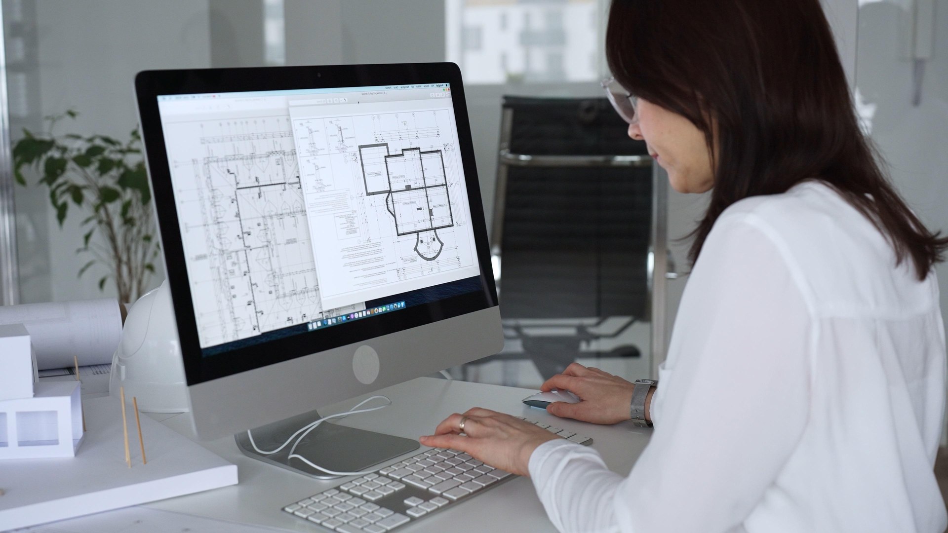 Engineering team reviewing technical drawings around a desk
